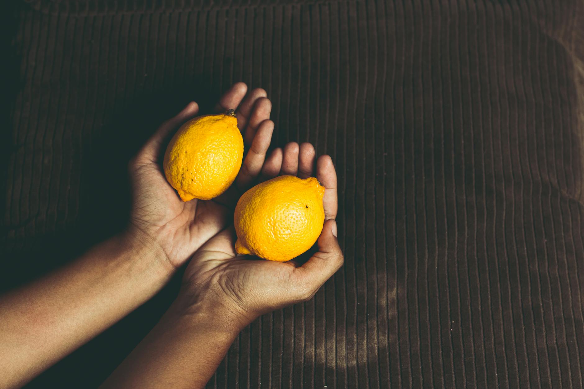 Two hands holding fresh lemons, symbolizing sensory grounding and present-moment awareness