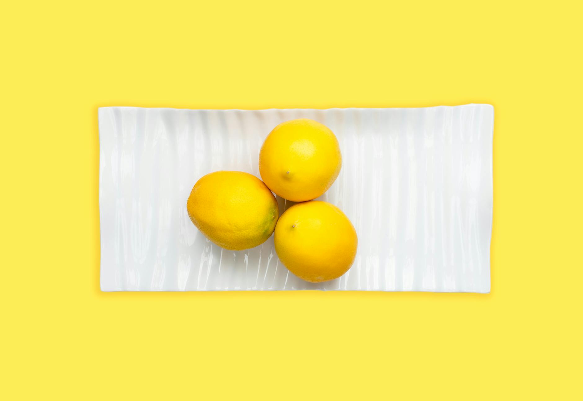 A yellow silicone vibrator surrounded by peeled bananas on a bright yellow background
