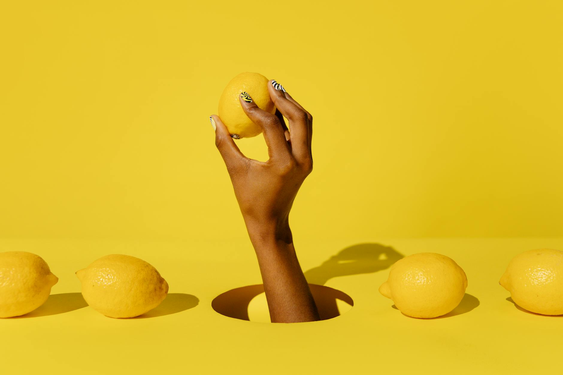 Hand holding a bright yellow lemon against a vivid yellow background, symbolizing natural rhythm and timing