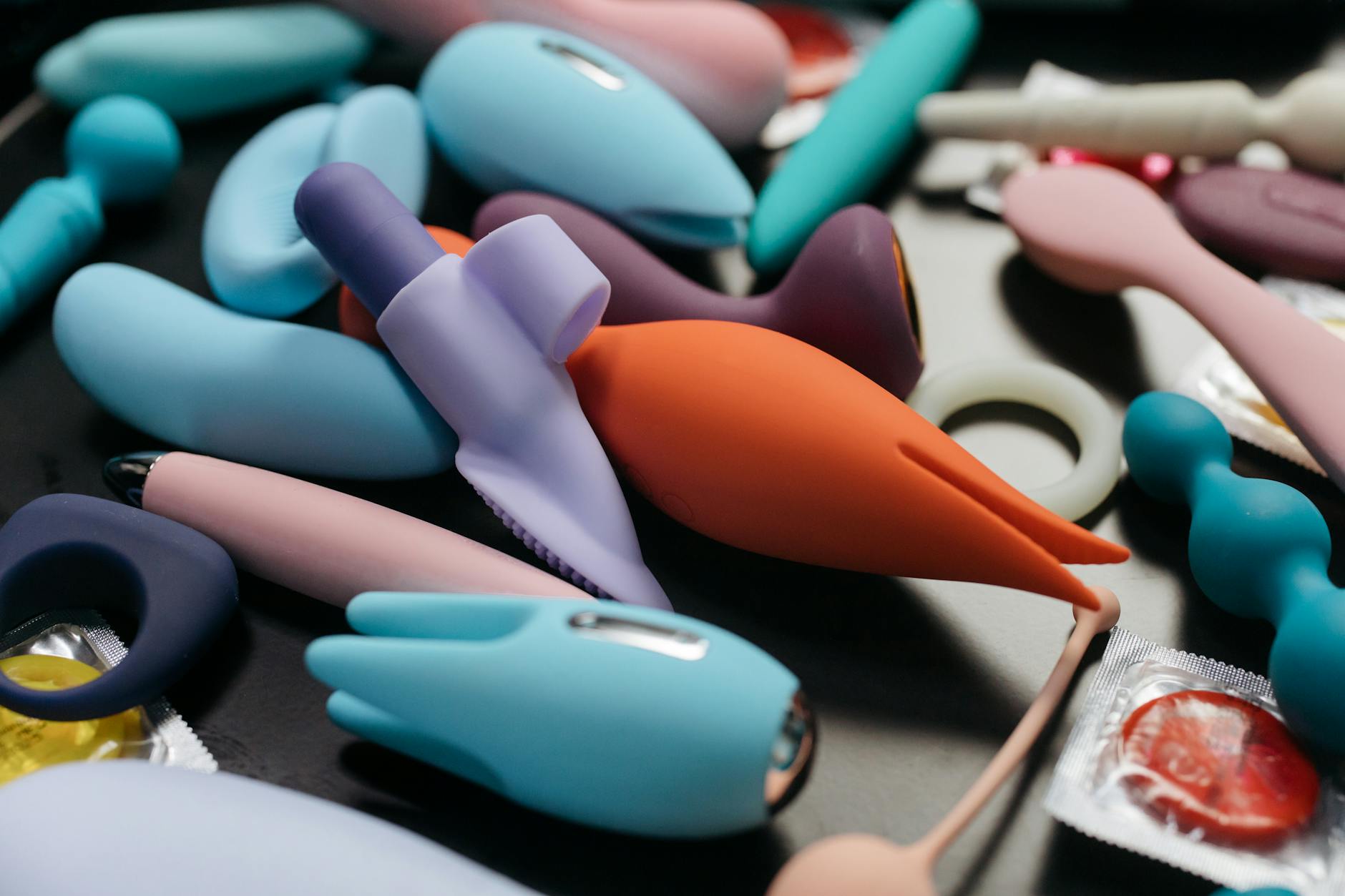 Woman holding colorful personal massagers with a thoughtful expression